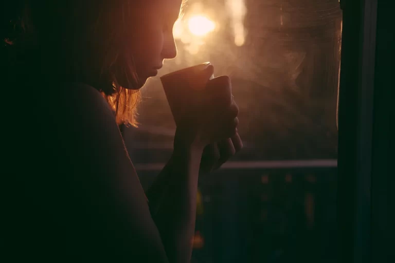 Vrouw drinkt koffie in de avond, passend bij cafeïne en de invloed op je nachtrust.