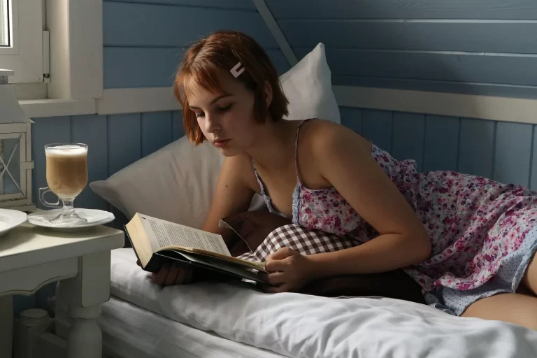 Rustig lezen in bed met een warme drank, passend bij ontspanning voor het slapengaan.