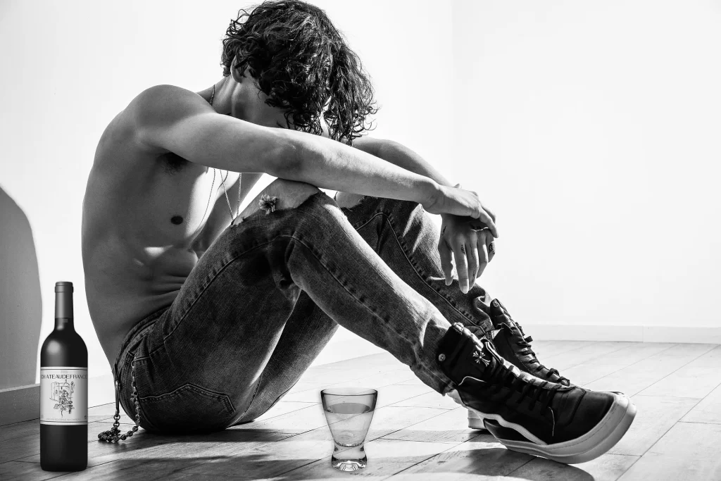 Man zit naast een fles alcohol, passend bij de invloed van alcohol op slaap en nachtrust.